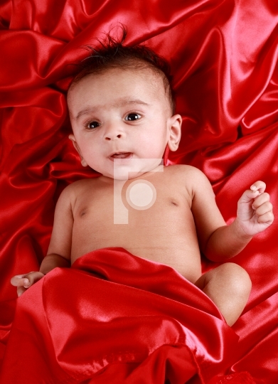 Baby boy with red satin background