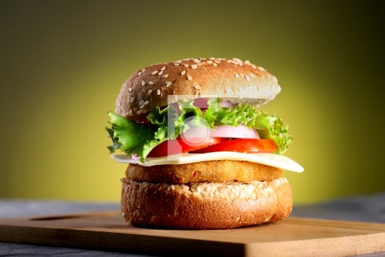 Fast Food - Burger on a wooden board and yellow background