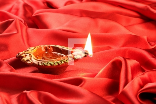 Handmade Diwali Clay Lamp on Red Satin Background