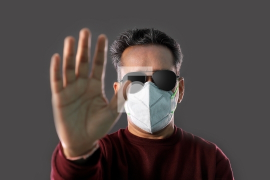 Indian Man wearing a N95 mask and sunglasses showing hands to st
