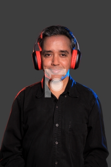 Indian man with wireless headphones on grey background