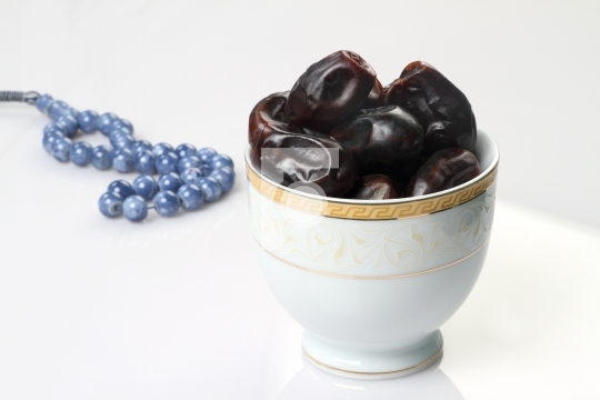 Ramadan fresh dates in a white bowl with rosary