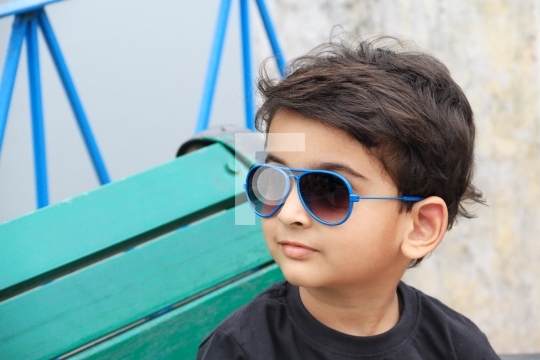 Smart Indian Toddler Boy with Sunglasses on a Bench