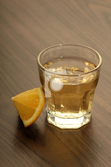 Tequila shot with lemon on a wooden table