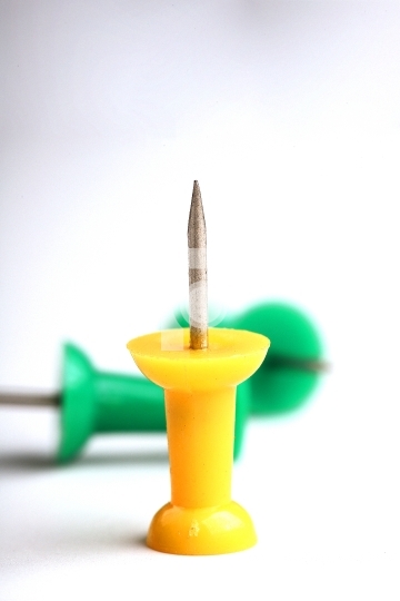 Yellow colored Push Pin or Thumb tack with green in the backgrou